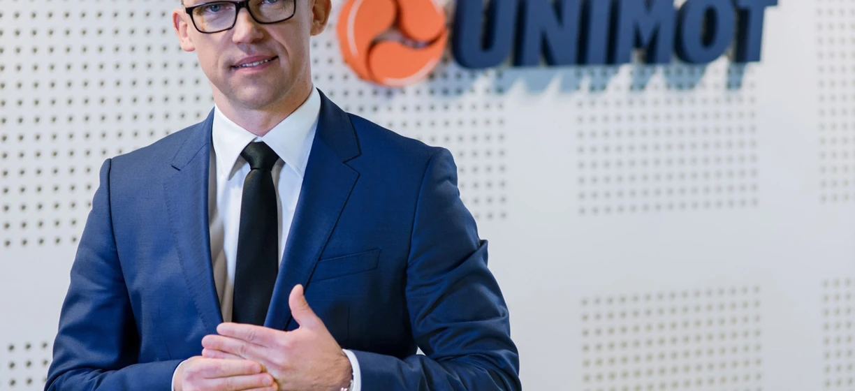 A white-collar worker in formal wear with a blazer and dress shirt showcasing the UNIMOT logo. Professional attire for a tech job.