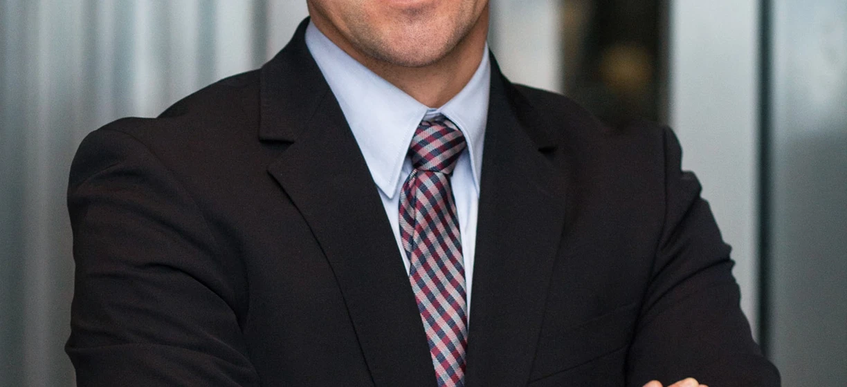 A man in formal wear smiles, wearing glasses with a collar and rolled-up sleeves. Vision care is important for a polished look.