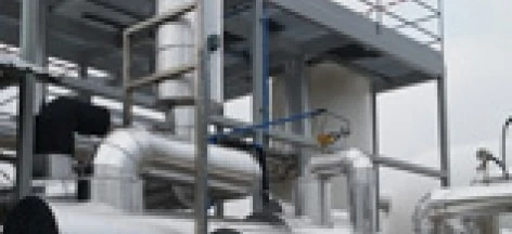 A close-up of a metal pipeline being manufactured by a machine in an industrial setting, made of composite materials. Iron and steel casing pipes are visible, showcasing the engineering processes involved.
