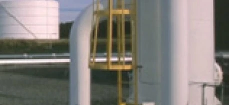 A metal pipe connected to a storage tank in an industrial setting. Engineering and machine at work with composite materials.