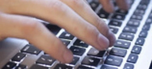 A person's finger typing on a computer keyboard, an essential input device for office equipment. Enhance your productivity with this electronic peripheral.