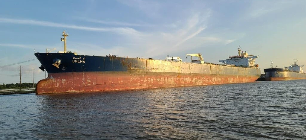 A large oil tanker ship sails through the water under a cloudy sky. The naval architecture of the boat is impressive as it carries a cargo of liquid.