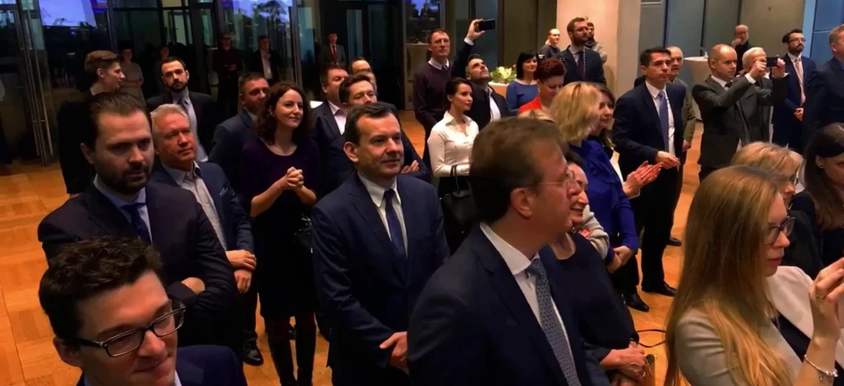 Grupa ludzi w strojach formalnych stojących razem, w tym pracownicy umysłowi w garniturach i marynarkach. Uczestnicy konferencji CHA nawiązujący kontakty.