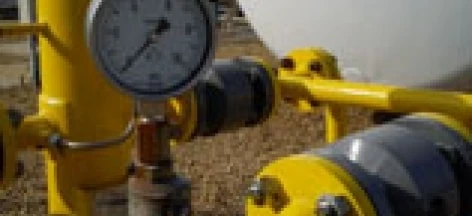 A industrial machine featuring a pipe, cylinder, and storage tank with plumbing valves and fittings made of steel. Measurements being taken on the equipment.
