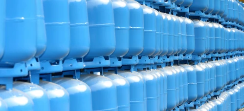 A plastic storage tank on a factory floor, surrounded by pipes and other machinery for mass production.
