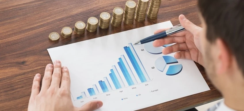 A businessperson's finger pointing at a diagram on a whiteboard in an office setting. Management gesture with thumb, office supplies and writing implement visible. Business planning for Jun, Feb, Ma, Apr, May, Q1 in Asia, US, Europe.