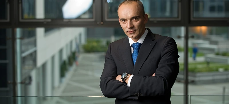 Pracownik umysłowy pewnie stojący w garniturze z marynarką i krawatem. Klasyczny i profesjonalny strój na sukces w biznesie.