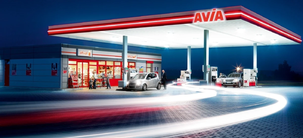 Gasoline filling station with a modern machine dispensing fuel. A shop is conveniently located next to the pumps at AVIA.