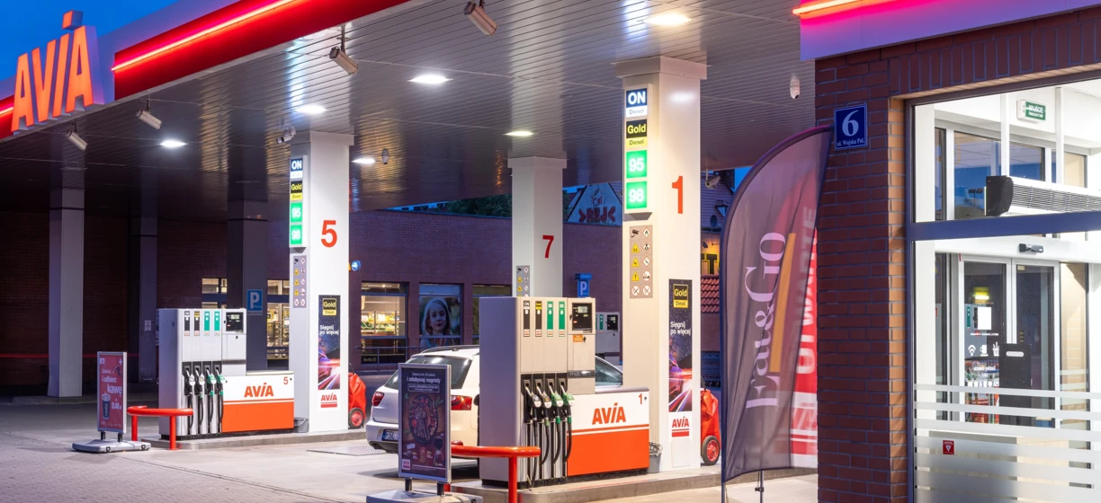 Neon electronic signage at a fuel filling station with a fuel dispenser for gasoline by AVÍA. Eat&Go and SD Eibar Channel 5 branding.