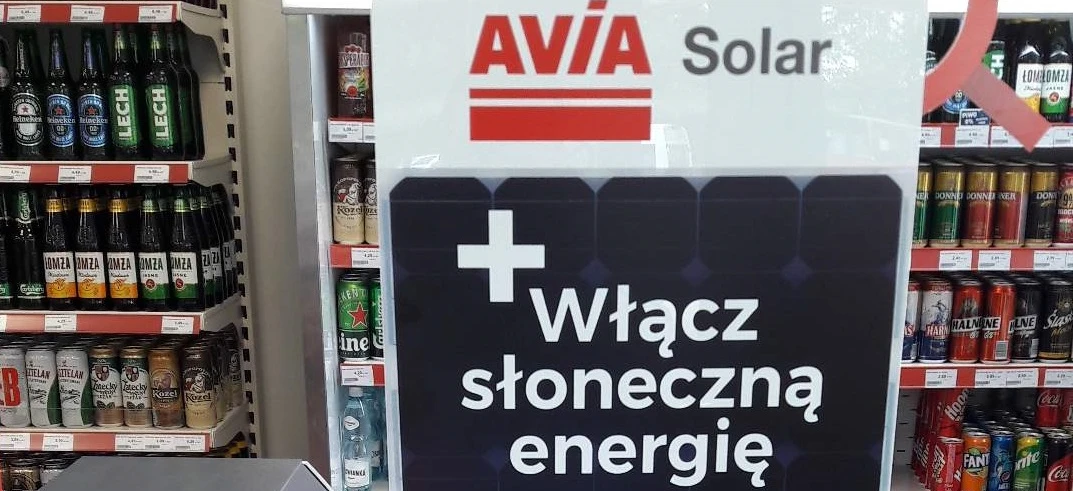 Image of a colorful advertisement with various brand names like Folne, ke, TELAN, Kozel, Kuzel, and LECH. The ad promotes solar energy with the words "Włącz słoneczną energię" prominently displayed. Local businesses like LOMOMZA and NER are also featured.