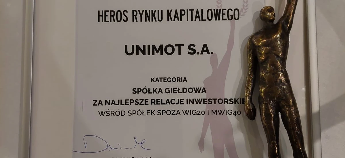 Award for Best Investor Relations among non-WIG20 and MWIG40 companies. Presented to UNIMOT S.A. by the Association of Individual Investors. Jarosław Dominiak, President of the Association, accepts the trophy on a podium with a brass banner.