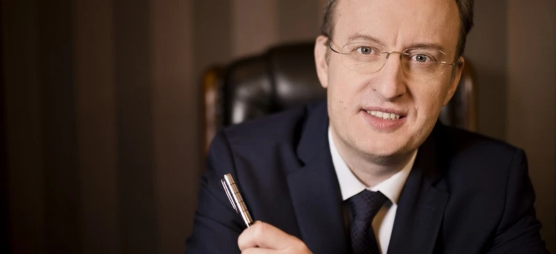 A close-up of a person wearing eyewear and a suit with their finger resting on their chin. Vision care and formal wear are highlighted in this image.