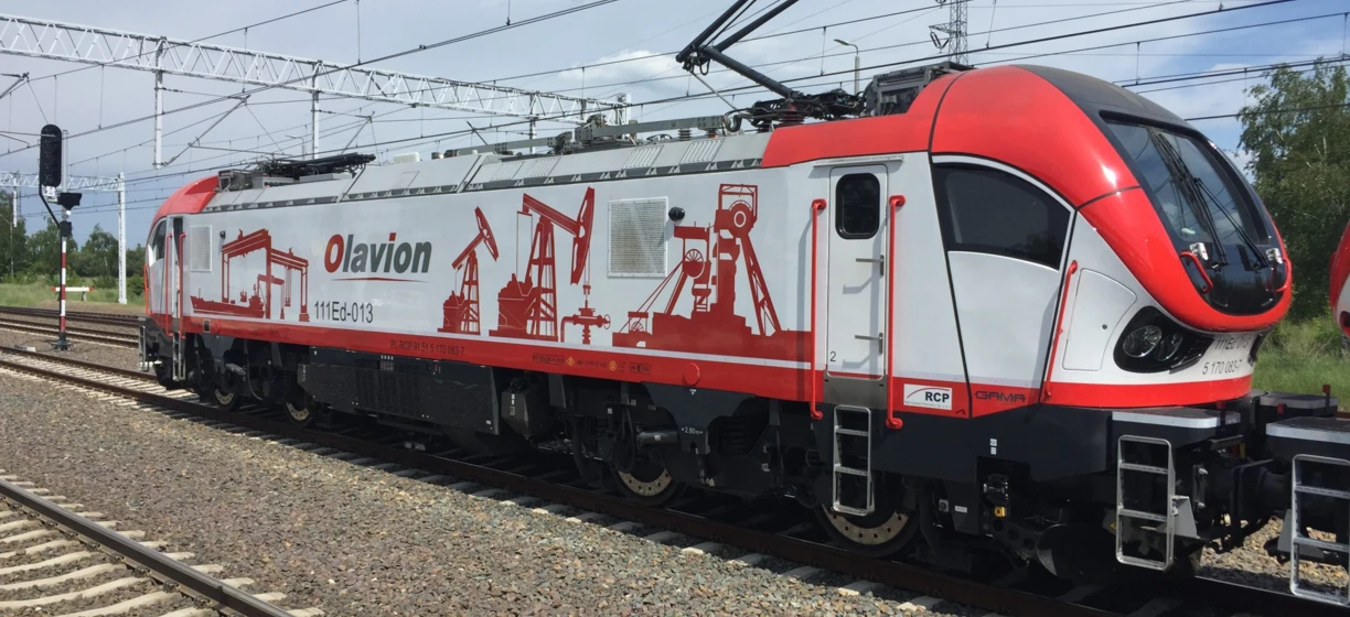 An electric locomotive on the tracks under an overhead power line. Public transport with sleek rolling stock. Olavion train on the electrical network.