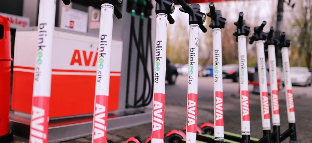 Advertisement for AVIA bicycles featuring a close-up of a bicycle frame, wheel, handlebar, fork, tire, and spokes. Blinky lights add a touch of safety and style. Explore the city with AVIA bikes! #AVIA #bicycles #citylife #safety #style