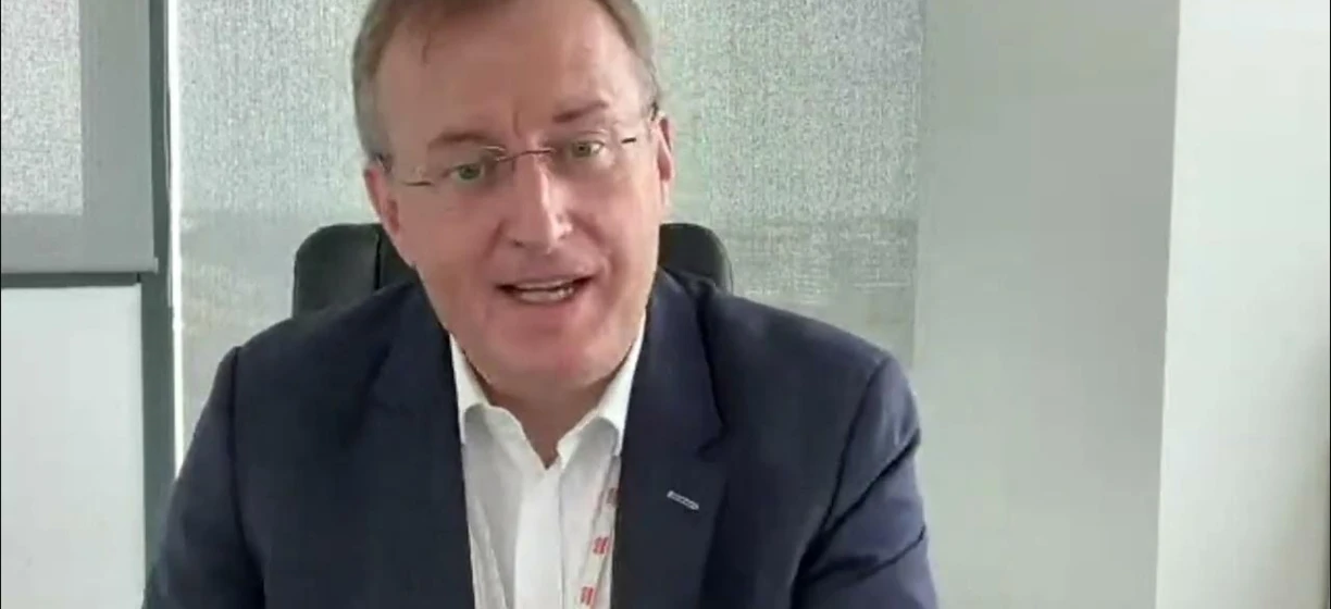 Mężczyzna w formalnym ubraniu ze szkłami stojący pewnie, zidentyfikowany jako Adam Sikorski. Modne okulary, koszula i czysty biały kołnierz.