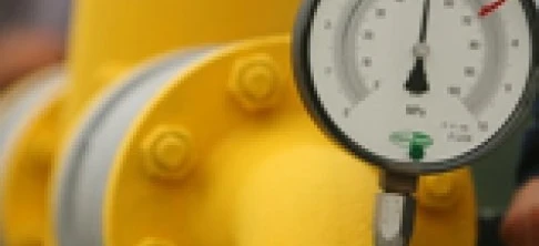 A yellow plastic pipe with a gauge and valve attached, seen on a machine used for measuring in plumbing.