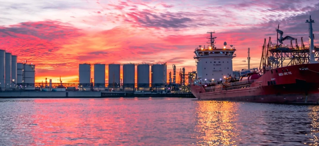 A dusk view of a ship at port, a watercraft used for freight transport. Naval architecture meets machine in this transport on the waterway.