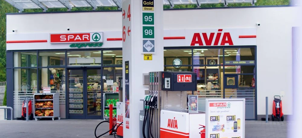 A gas station with various fuel options such as Diesel, Gold, and LPG. A sport utility vehicle is parked at the fuel dispenser, ready for refueling. ON, SPAR, and other signage visible.