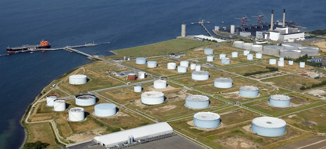 A large storage tank and silo at an industrial power station. The factory is bustling with activity.