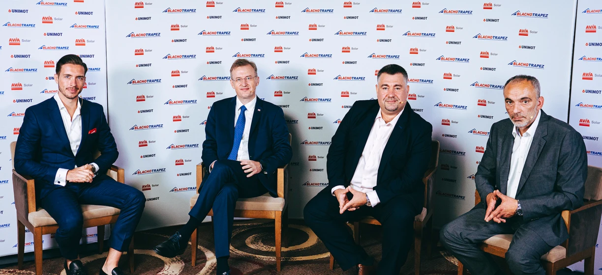 A man in formal wear smiling, standing in a blazer, white dress shirt, and necktie. Keywords: Blachotrapez, AVIA Solar, UNIMOT.
