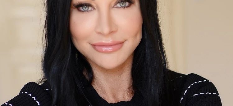 A smiling woman with long black hair, perfectly shaped eyebrows, full lips, and stunning eyelashes. Her beautifully layered hair is styled in a step cut, enhancing her beauty.