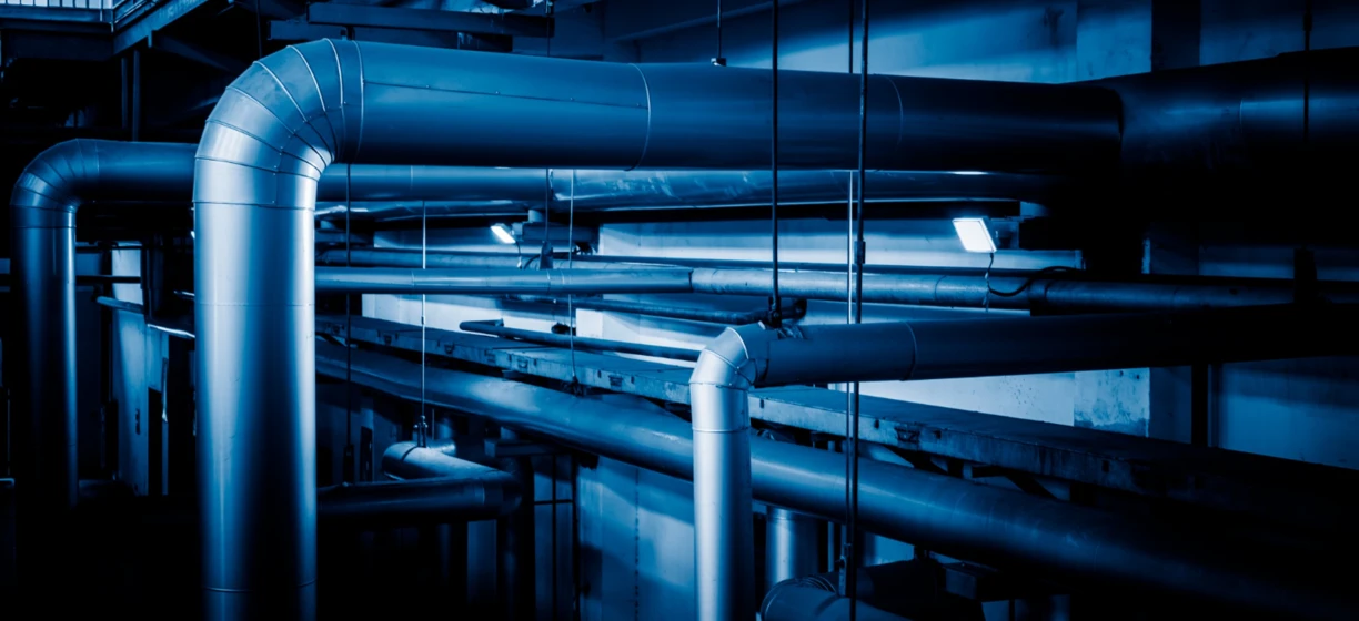 Metaliczna rura przemysłowa wytwarzana przez maszynę w środowisku przemysłowym. Stalowa obudowa rury kształtowana do projektów instalacji wodno-kanalizacyjnych i inżynieryjnych.