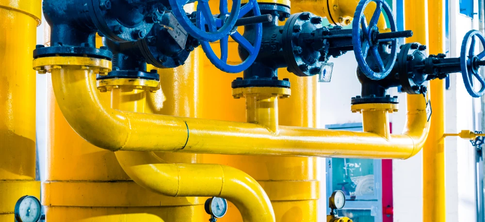 Metalowa walcowata rura połączona z rurami w stacji pompowniczej, prezentująca technologię przemysłowej hydrauliki w branży inżynieryjnej.
