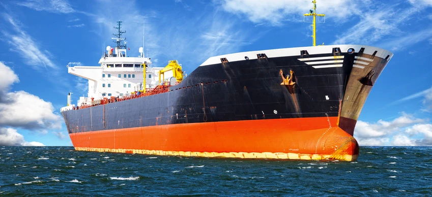 A cargo ship on the ocean, possibly an oil tanker, with naval architecture in focus. In the background, a sea freight transport vessel.