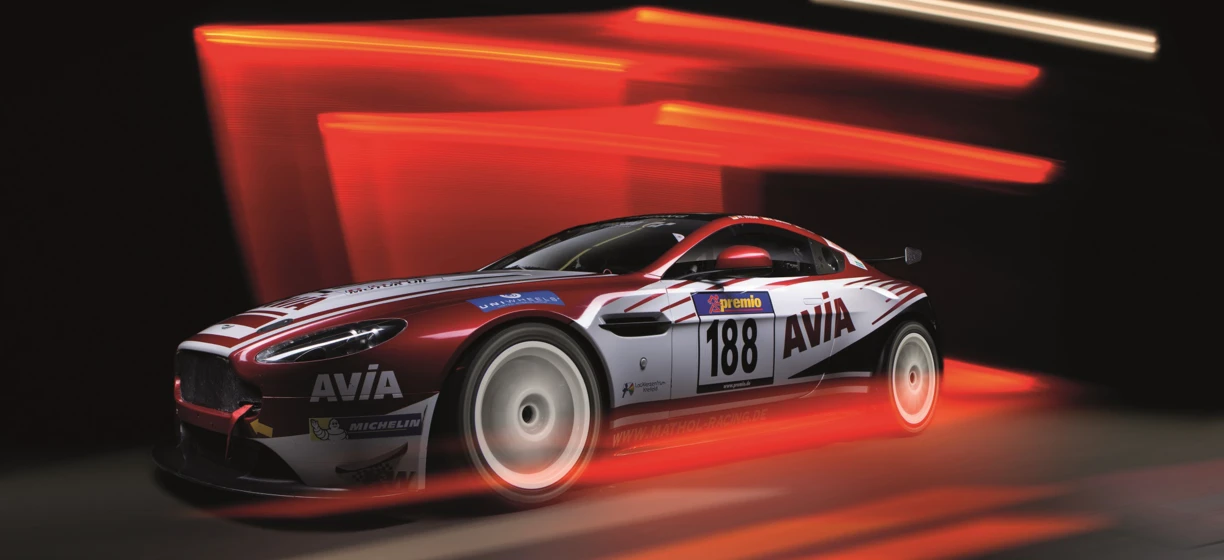 Lśniący samochód sportowy na torze wyścigowym z logo sponsorów AVIA, MICHELIN, UNIWHEELB, lackiezentrum, Krefeld i premio. Odwiedź stronę www.MATHOL RACING.DE dla więcej informacji. #WyścigiSamochodowe #SamochódSportowy