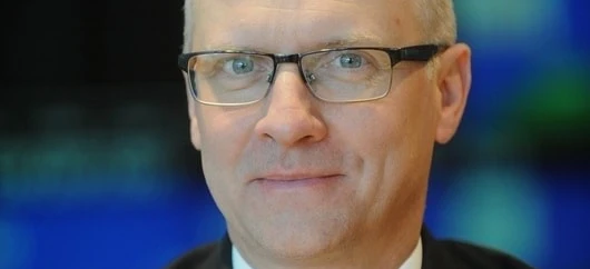 A person with glasses with their chin resting on their cheek and a collar visible. Close-up shot of eyewear on a face.