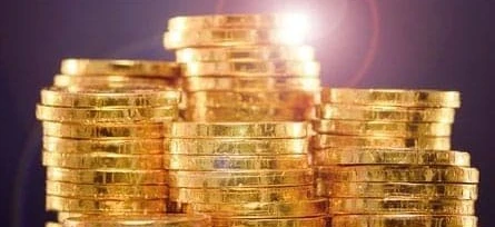 Close-up of shiny gold coins symbolizing wealth and saving money. Hand holding a stack of cash, representing financial security and currency handling.