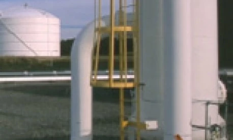 A metal pipe connected to a storage tank in an industrial setting. Engineering and machine at work with composite materials.