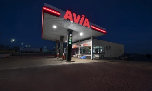 A fuel station sign in Polish displaying information about AVIA ON Gold 98 fuel. Includes a shop on site.