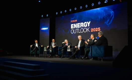Pracownik biurowy w garniturze stoi na scenie pronuncjując przemowę podczas wydarzenia publicznego forum UNIMOT Energy Outlook 2025.