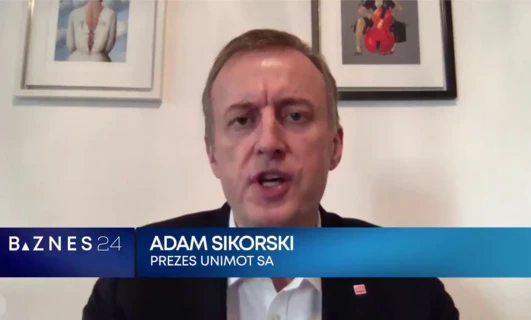 Portret Adama Sikorskiego, CEO UNIMOT SA, ubranego w elegancki garnitur z białą koszulą i krawatem. Wyrażający profesjonalizm i pewność siebie w swoim stroju.