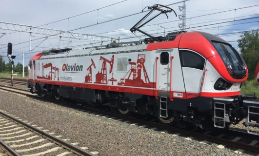 Elektryczna lokomotywa podróżująca po torach kolejowych pod liniami zasilania z góry. Pojazd publicznego transportu kolejowego część sieci elektrycznej. Numerowany pociąg Olavion w ruchu.