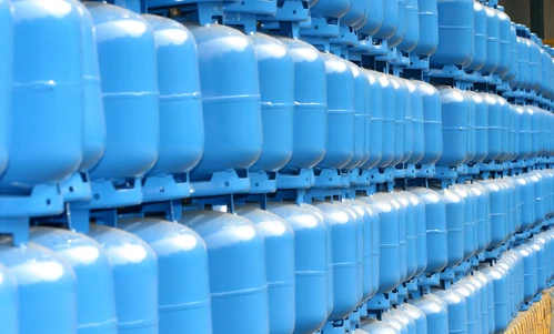 A plastic storage tank on a factory floor, surrounded by pipes and other machinery for mass production.