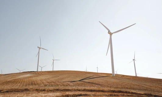 Turbina wiatrowa stojąca wysoko na obszernym polu w ecoregionie, zrównoważony źródło energii dla publicznej użyteczności.