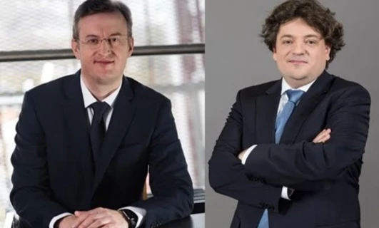 Mężczyzna w eleganckim garniturze i płaszczu pewnie stojący, z wydatnym kołnierzem otaczającym twarz i czoło. Klasyczny okrycie wierzchnie dla eleganckiego wyglądu.