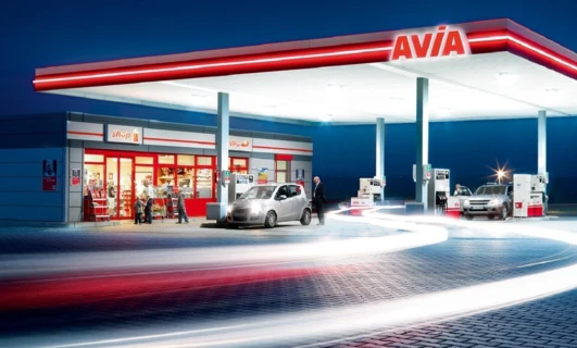 Gasoline filling station with a modern machine dispensing fuel. A shop is conveniently located next to the pumps at AVIA.