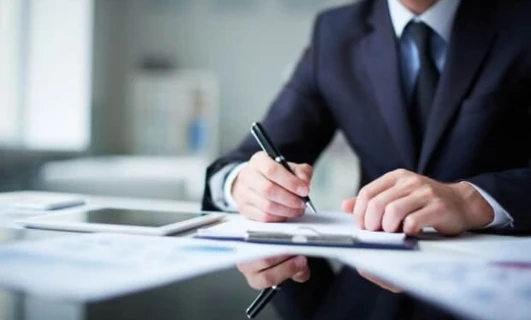 A white-collar worker sitting at a desk with office supplies, job-related equipment, and learning materials.