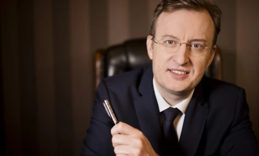 A close-up of a person wearing eyewear and a suit with their finger resting on their chin. Vision care and formal wear are highlighted in this image.