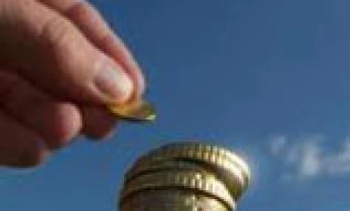 A hand holding a stack of dollar bills symbolizing money handling and saving. Currency, cash, banknote, coin in background.