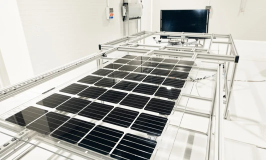 A sleek, modern machine conducting engineering work on metal and steel components, exemplifying precision and cleanliness. Solar panels in the background hint at a focus on sustainable energy technologies.