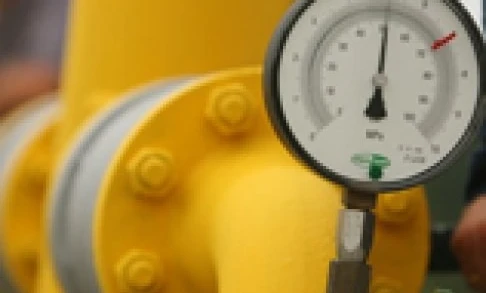 A yellow plastic pipe with a gauge and valve attached, seen on a machine used for measuring in plumbing.