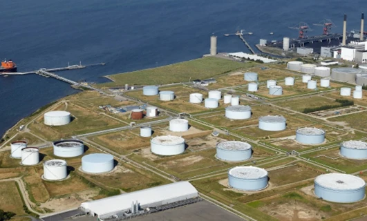 A large storage tank and silo at an industrial power station. The factory is bustling with activity.