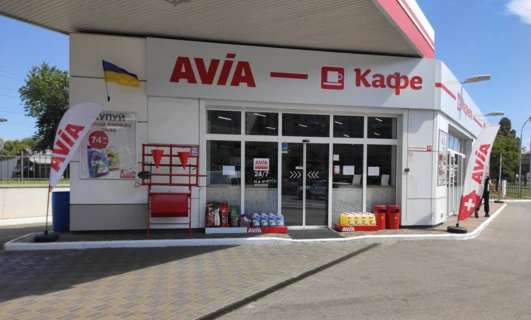 Reklama dla lekkich samochodów dostawczych AVIA o numerze VIN 7499. Zaparkowane na wyznaczonym miejscu z kołpakami oraz włączonymi światłami stopu i hamowania. Wyraźnie wyświetlone logo oraz informacje kontaktowe.