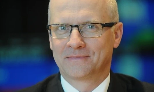 A person with glasses with their chin resting on their cheek and a collar visible. Close-up shot of eyewear on a face.