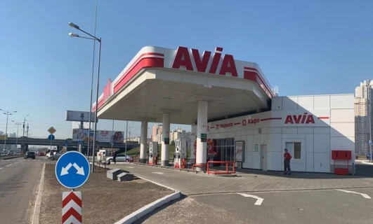 A sport utility vehicle parked at a filling station with a reflective rear-view mirror and tail & brake light. AVIA gas station in Poland.
