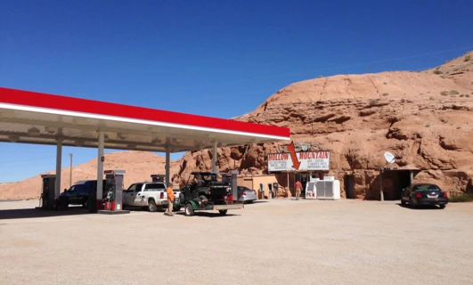 Title: Gas station at Hollow Mountain: supplies for road trip in aeolian landform. Truck fills up with gasoline next to geological formation.  Ice cold drinks, snacks, beer, souvenirs, and more available. #travel #outdoors #fuelstation #geology